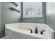 A sleek soaking tub features modern black fixtures and a window with blinds for natural light at 142 Holly Mill Village Dr, Canton, GA 30114