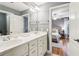 Bathroom showcasing double vanity with white cabinets and view to bedroom with ceiling fan and hard wood floors at 2452 Stone Manor Ne Dr, Buford, GA 30519