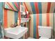 Small bathroom with single sink, toilet, and colorful striped wallpaper at 3196 Windfield Cir, Tucker, GA 30084