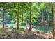 Scenic backyard featuring lush greenery, lake, dock, and boat for outdoor enjoyment at 6077 Lake Lanier Heights Rd, Buford, GA 30518
