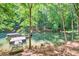 Lakefront backyard with dock and boat nestled among lush green trees for a serene view at 6077 Lake Lanier Heights Rd, Buford, GA 30518
