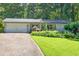 Charming home featuring a well-manicured lawn and inviting curb appeal with mature trees and landscaping at 6077 Lake Lanier Heights Rd, Buford, GA 30518