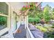 Inviting front porch with a cozy bench and charming decor, surrounded by lush landscaping and flowering plants at 6077 Lake Lanier Heights Rd, Buford, GA 30518