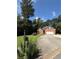 Quaint brick home boasts a well-manicured lawn, long driveway, and charming mailbox, nestled amidst lush trees and a vibrant blue sky at 709 Stonehenge Pl, Jonesboro, GA 30236