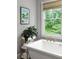 Bright bathroom showcasing a soaking tub, gold fixtures, and serene views of lush greenery at 127 Oak Ln, Decatur, GA 30030