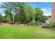 Lush backyard with a well-maintained lawn, beautiful landscaping, and a glimpse of a pool area at 7025 Windsor Hill Psge, Suwanee, GA 30024