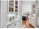 Butler's pantry with glass display cabinets and decorative backsplash offers extra storage and convenience at 7025 Windsor Hill Psge, Suwanee, GA 30024