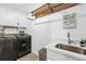 Laundry room featuring white cabinetry, countertop sink, modern fixtures and appliances at 7025 Windsor Hill Psge, Suwanee, GA 30024