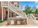 An inviting outdoor kitchen boasts a stone-clad island with a built-in grill and convenient access to the deck at 7025 Windsor Hill Psge, Suwanee, GA 30024