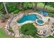 Resort-style pool with a spa, stone waterfall, surrounding rock features, and outdoor seating area at 7025 Windsor Hill Psge, Suwanee, GA 30024