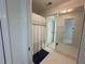 Bright bathroom featuring white tiled floors, a shower with a patterned curtain, and mirrored closet door at 810 Doe Hill Ln, Roswell, GA 30075