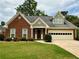 Charming brick home with a two-car garage, dormer window, manicured lawn, and lush green landscaping at 810 Doe Hill Ln, Roswell, GA 30075
