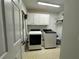Efficient laundry room with side-by-side washer and dryer, overhead cabinets, and organized shelving for convenience at 810 Doe Hill Ln, Roswell, GA 30075
