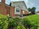 Home exterior with a brick chimney, green siding, manicured hedges, and colorful hydrangeas at 810 Doe Hill Ln, Roswell, GA 30075