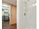 Walk-in shower with white tile surround, rainfall shower head, and wood floors at 300 Stone Mill Trl, Atlanta, GA 30328