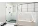 Bathroom featuring white subway tiles, glass shower, large windows, and a tub with sleek, modern fixtures at 1232 Lucile Sw Ave, Atlanta, GA 30310