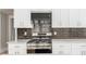 Close up of a stainless steel gas range with black backsplash, white cabinets, and white countertops at 1232 Lucile Sw Ave, Atlanta, GA 30310
