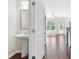 A modern bathroom with a pedestal sink and a view into a bright, open living area at 5843 Taka Ln, Lithonia, GA 30038