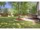 This backyard includes a deck with grill, a seating area with gravel, a lush lawn, and mature trees at 410 Sheringham Ct, Roswell, GA 30076