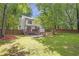 A lush backyard with a deck, fire pit, privacy fence, and ample green space surrounded by mature trees at 410 Sheringham Ct, Roswell, GA 30076