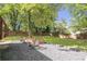 Landscaped backyard featuring a gravel patio, firepit, and mature trees, creating a serene outdoor living space at 410 Sheringham Ct, Roswell, GA 30076
