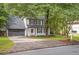 A traditional two-story home featuring a long driveway, well-maintained lawn, and classic black and white color scheme at 410 Sheringham Ct, Roswell, GA 30076
