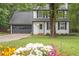 Charming two-story home with a dark gray garage door, manicured lawn, and flowerbeds at the front at 410 Sheringham Ct, Roswell, GA 30076