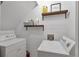 Bright laundry room with white shiplap walls and floating shelves for storage at 410 Sheringham Ct, Roswell, GA 30076