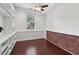 Bright office featuring hardwood floors, brick accent wall, built-in shelving, and a ceiling fan at 4046 Water Hole Ct, Douglasville, GA 30135