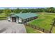 Well-maintained barn exterior with a green metal roof, multiple stalls, and a fenced pasture, creating an ideal equestrian setup at 14501 Woolsey Rd, Hampton, GA 30228