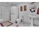 A well-lit bathroom features a pedestal sink, stacked washer and dryer, and modern fixtures at 14501 Woolsey Rd, Hampton, GA 30228