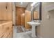 Well-lit bathroom with a pedestal sink, wood accents, and marble flooring, creating a refined space at 14501 Woolsey Rd, Hampton, GA 30228