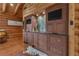 A log cabin wet bar area featuring wooden cabinets, sink, granite countertops, and dual TVs at 14501 Woolsey Rd, Hampton, GA 30228