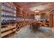A fully stocked wine cellar with custom wood shelving, stone floors, and a tasting table and chairs at 14501 Woolsey Rd, Hampton, GA 30228