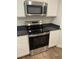 Close-up of a stainless steel stove and microwave with white cabinets and dark granite countertops at 746 Great Oak Pl, Villa Rica, GA 30180