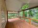 A relaxing back porch with wooden flooring and railings, offering a tranquil view of the lush trees at 851 Millvale Pl, Lawrenceville, GA 30044