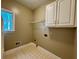 A functional laundry room with tile floors, storage cabinets, and natural light from a window at 851 Millvale Pl, Lawrenceville, GA 30044