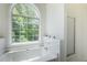 Bright bathroom showcasing a soaking tub and walk in shower with a large arched window at 733 Exchange Mill Pl, Dacula, GA 30019