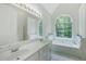 Bright bathroom featuring double sinks, soaking tub under arched window, and tiled floors at 733 Exchange Mill Pl, Dacula, GA 30019