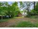 Backyard view of the detached brick house framed by mature trees and lush greenery at 1200 Mansfield Ne Ave, Atlanta, GA 30307
