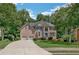 Charming two-story brick home with a two-car garage, lush landscaping, and a curved driveway at 1625 Hawkins Cove Trl, Roswell, GA 30076