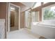 An elegant bathroom featuring a bathtub, an enclosed glass shower and white tiled flooring at 7392 N Mitchell N Ct, Villa Rica, GA 30180