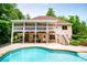 Two-story home exterior featuring a large back porch with stairs leading to the backyard pool and mature landscaping at 7392 N Mitchell N Ct, Villa Rica, GA 30180