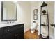 A stylish powder room featuring a black vanity, marble countertop, toilet, and elegant decor at 6017 Chestatee Creek Nw Ct, Acworth, GA 30101