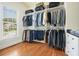 This walk-in closet features built-in shelves with hanging clothes, drawers, and a sunlit window at 6017 Chestatee Creek Nw Ct, Acworth, GA 30101
