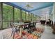 Inviting screened porch with dining and lounge areas, overlooks lush greenery, and a colorful rug at 6017 Chestatee Creek Nw Ct, Acworth, GA 30101