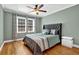 This bedroom features hardwood floors, a ceiling fan, and a queen bed with grey accents at 1875 Edgemont Ct, Cumming, GA 30041