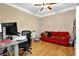 A home office includes a desk, red couch, and natural light from the window at 1875 Edgemont Ct, Cumming, GA 30041