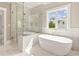 Bright bathroom featuring large tub, glass enclosed shower, and white marble flooring at 4525 Aiden Way, Cumming, GA 30041