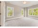 Bedroom featuring neutral colors, carpet, and three windows with natural light and wooded views at 4525 Aiden Way, Cumming, GA 30041